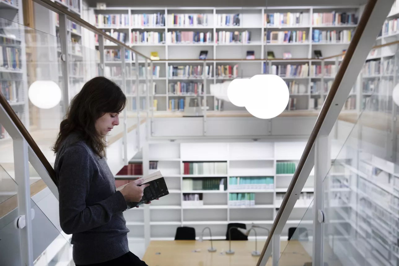Student läser bok stående i trappa. Foto Johan Bävman